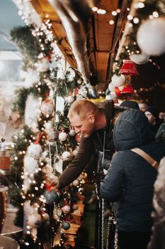 Holiday shoppers explore a Christmas market decorated with lights and ornaments in Budapest.