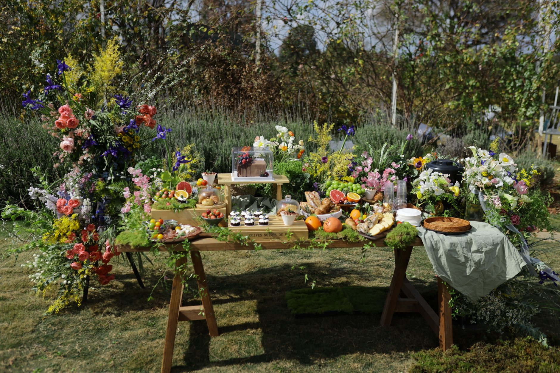 Beautiful outdoor party setup with vibrant flowers and a variety of foods on display.