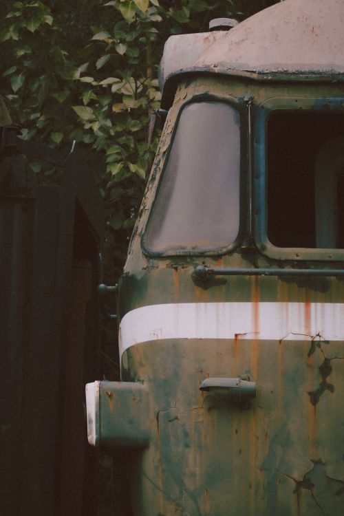 Free Old, rust-covered vehicle in an overgrown outdoor setting, showcasing decay. Stock Photo