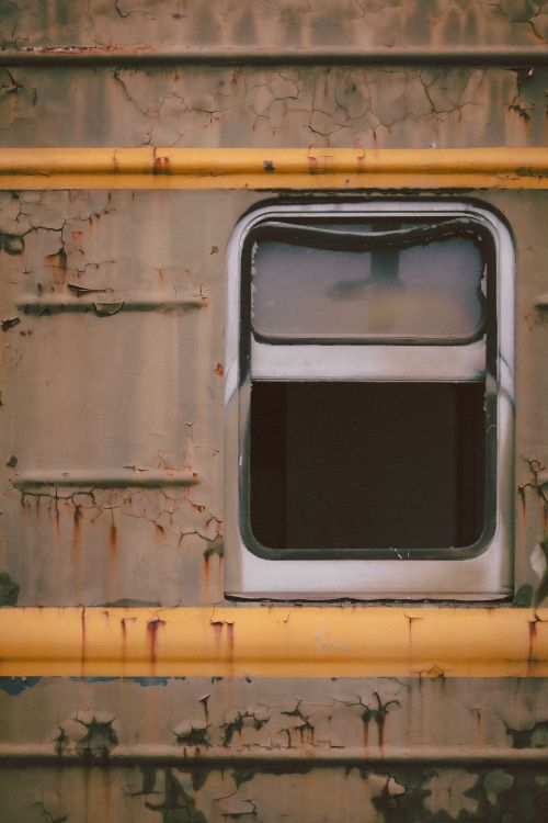 Free Close-up of a vintage train window with peeling paint and yellow accents, evoking a sense of nostalgia. Stock Photo