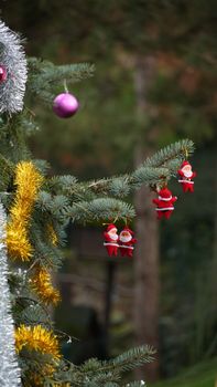 Close-up of a Christmas tree branch decorated with Santa ornaments and tinsel.
