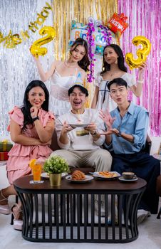 A group of friends celebrating a birthday with smiles and cake in a festive setting.