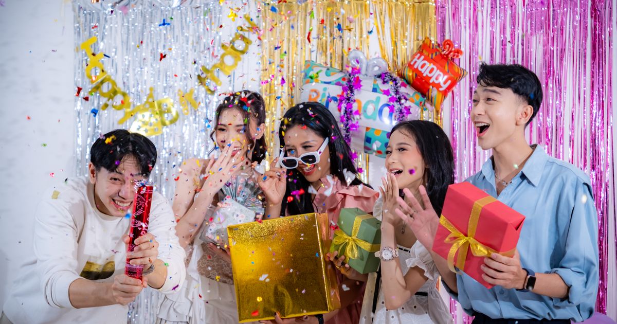 Group of friends celebrating a birthday with wrapped gifts and confetti