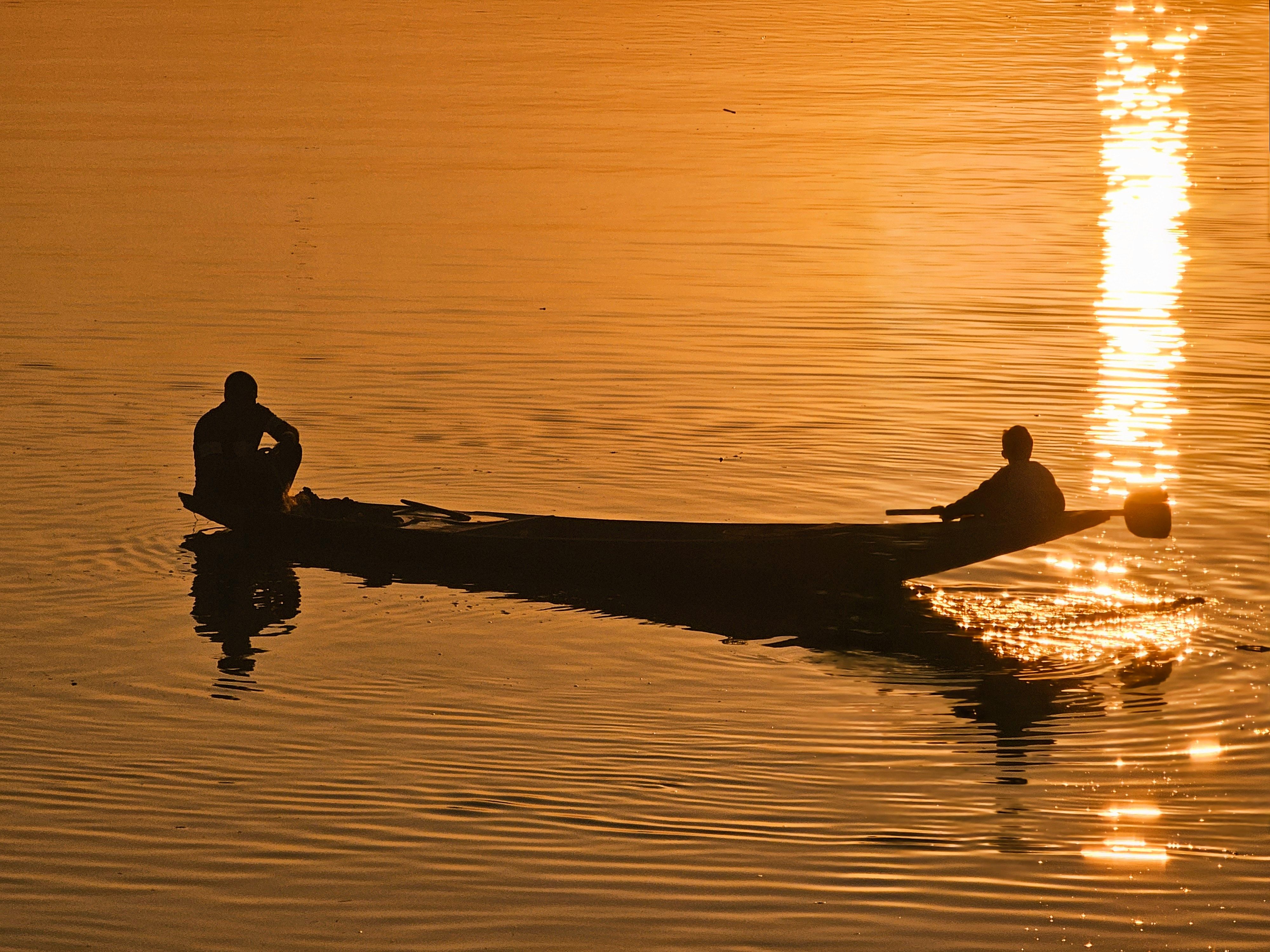 Serene Sunset Silhouette of Two People Rowing · Free Stock Photo
