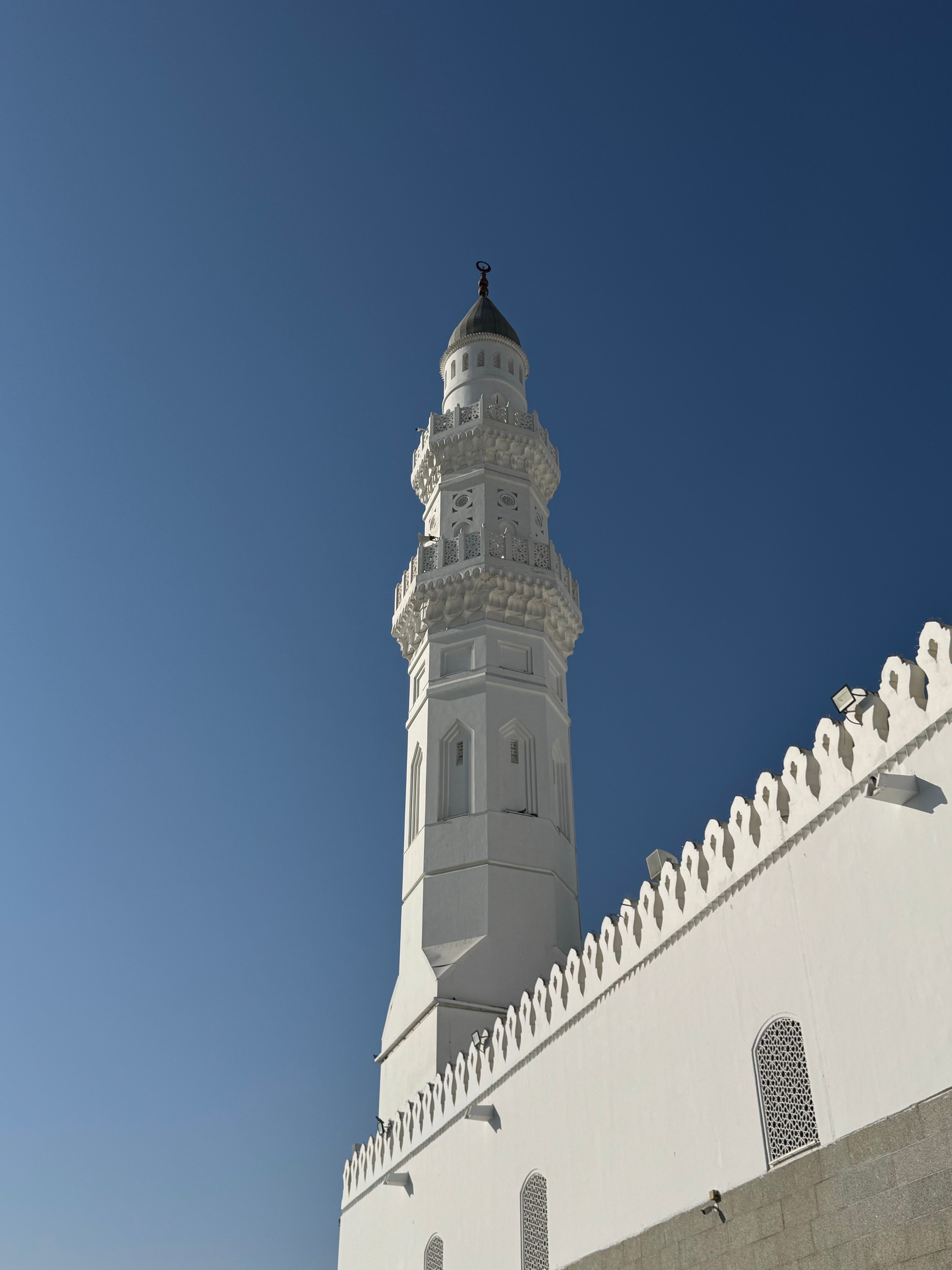 A beautiful white minaret reaching into the clear blue sky, showcasing Islamic architecture.