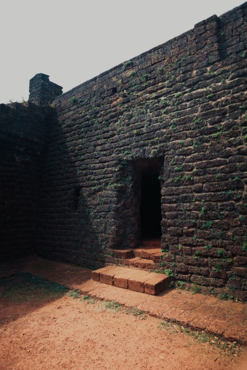Free Mysterious entrance of an ancient stone fortress with steps leading inside, under bright daylight. Stock Photo