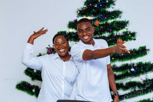 Two adults celebrating joyfully in front of a Christmas tree.