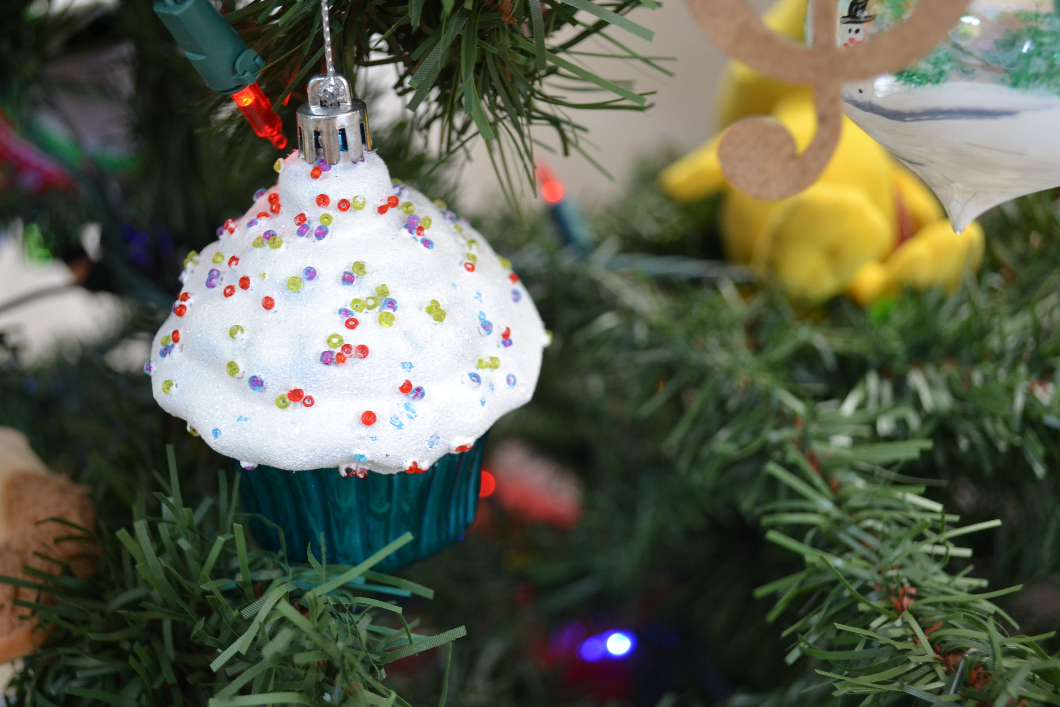 De franc Ornament de magdalena de colors amb espurnes penjades en una branca d'arbre de Nadal. Foto d'estoc