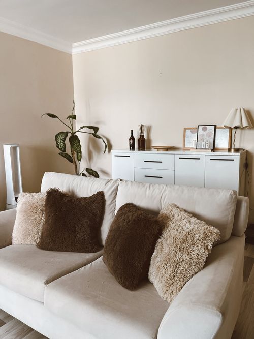 Free A stylish and cozy living room featuring a white sofa with fluffy cushions and modern decor. Stock Photo