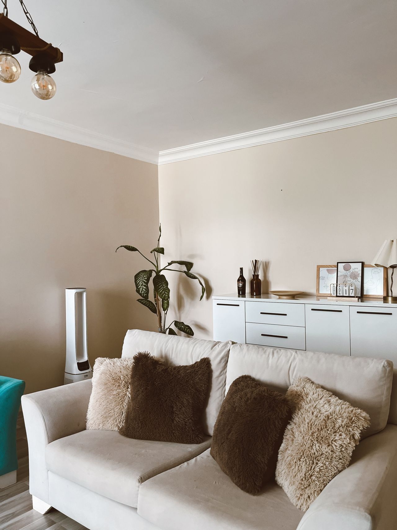 Cream sofa styled with brown cushions, a plant and a white sideboard