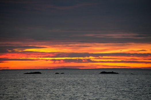 Breathtaking view of a vibrant sunset over the ocean with dramatic clouds.