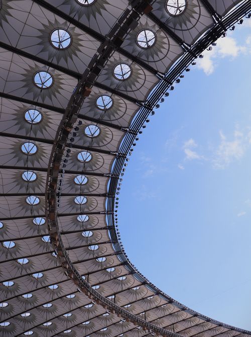 Free Curved stadium roof with circular windows against a clear blue sky, showcasing modern architecture. Stock Photo