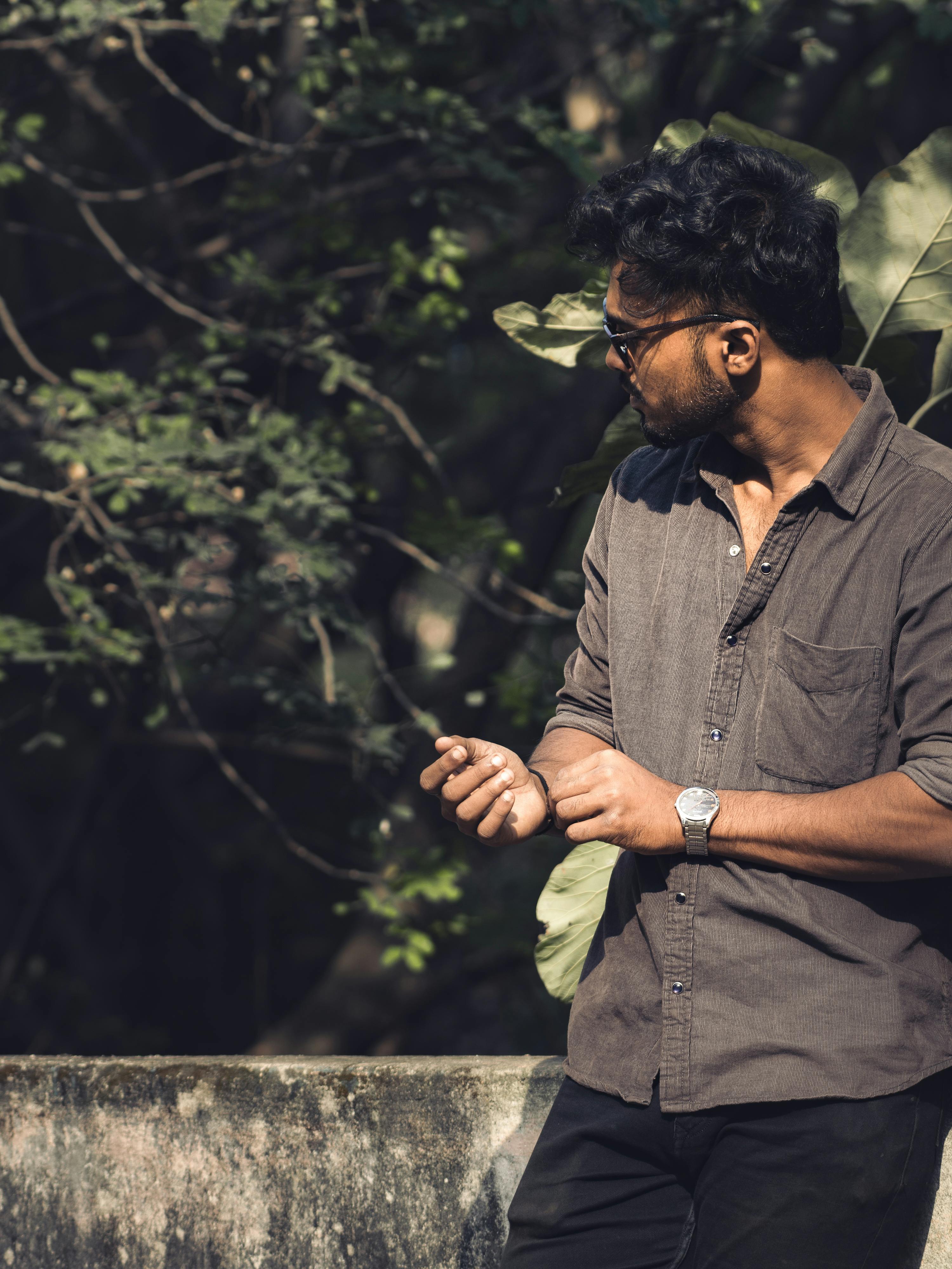 Miễn phí Chân dung một người đàn ông đeo kính râm, đứng ngoài trời giữa thiên nhiên với cây cối, mặc áo sơ mi cài cúc kiểu thường ngày. Ảnh lưu trữ