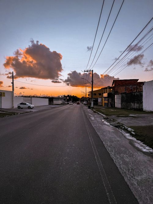 Free A quiet suburban street at sunset with vibrant clouds and empty road. Stock Photo