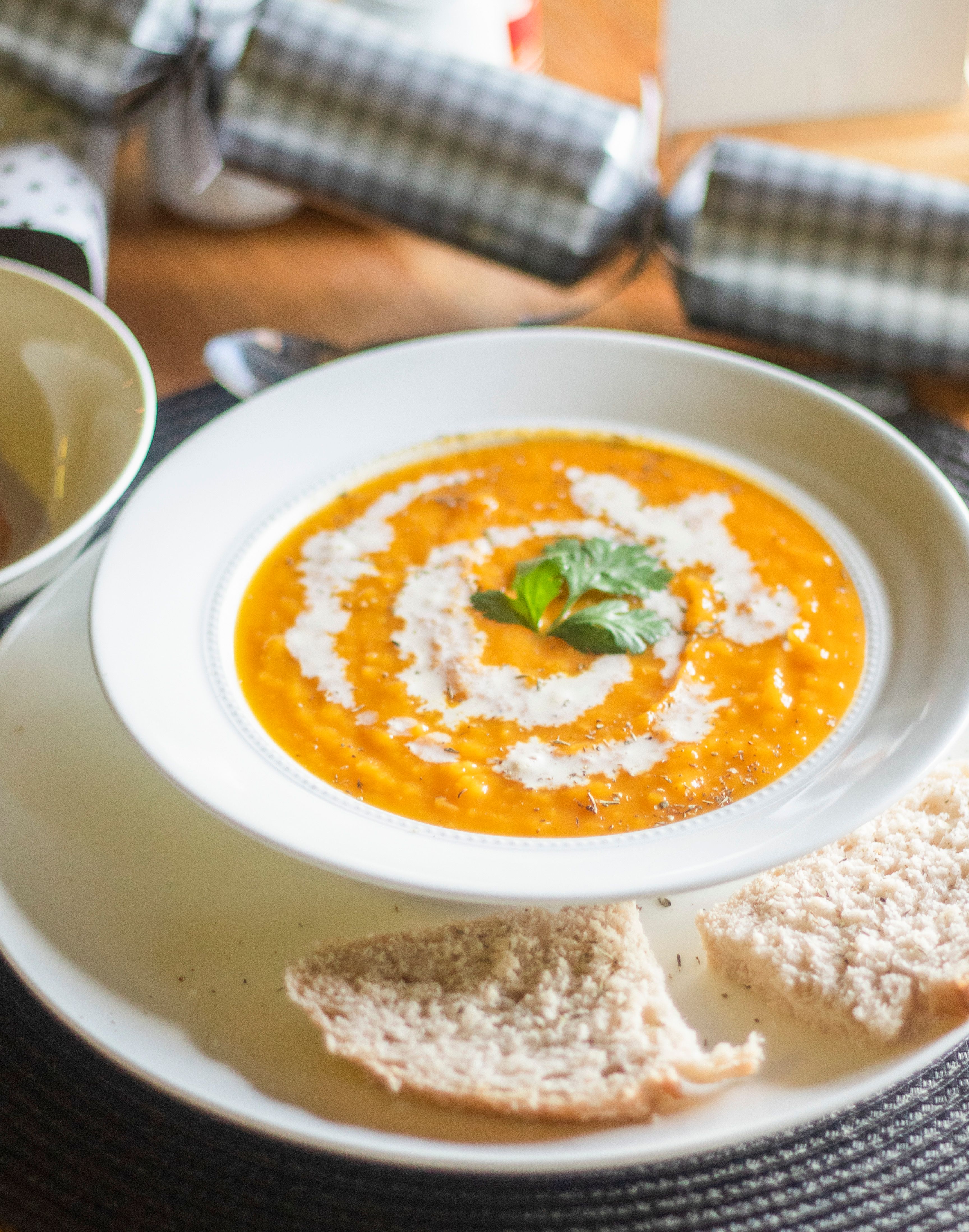 Delicious pumpkin soup garnished with cream and served with bread, perfect for cozy dining.
