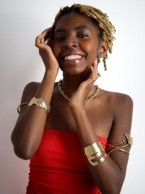 Free Radiant portrait of a joyful woman adorned with gold jewelry, showcasing elegance and style. Stock Photo
