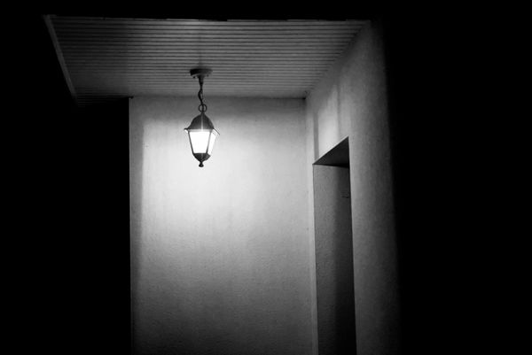 Lanterne suspendue éclairant un couloir sombre et vide en noir et blanc