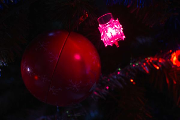 Boule de Noël rouge et lumière rose sur un sapin dans la pénombre