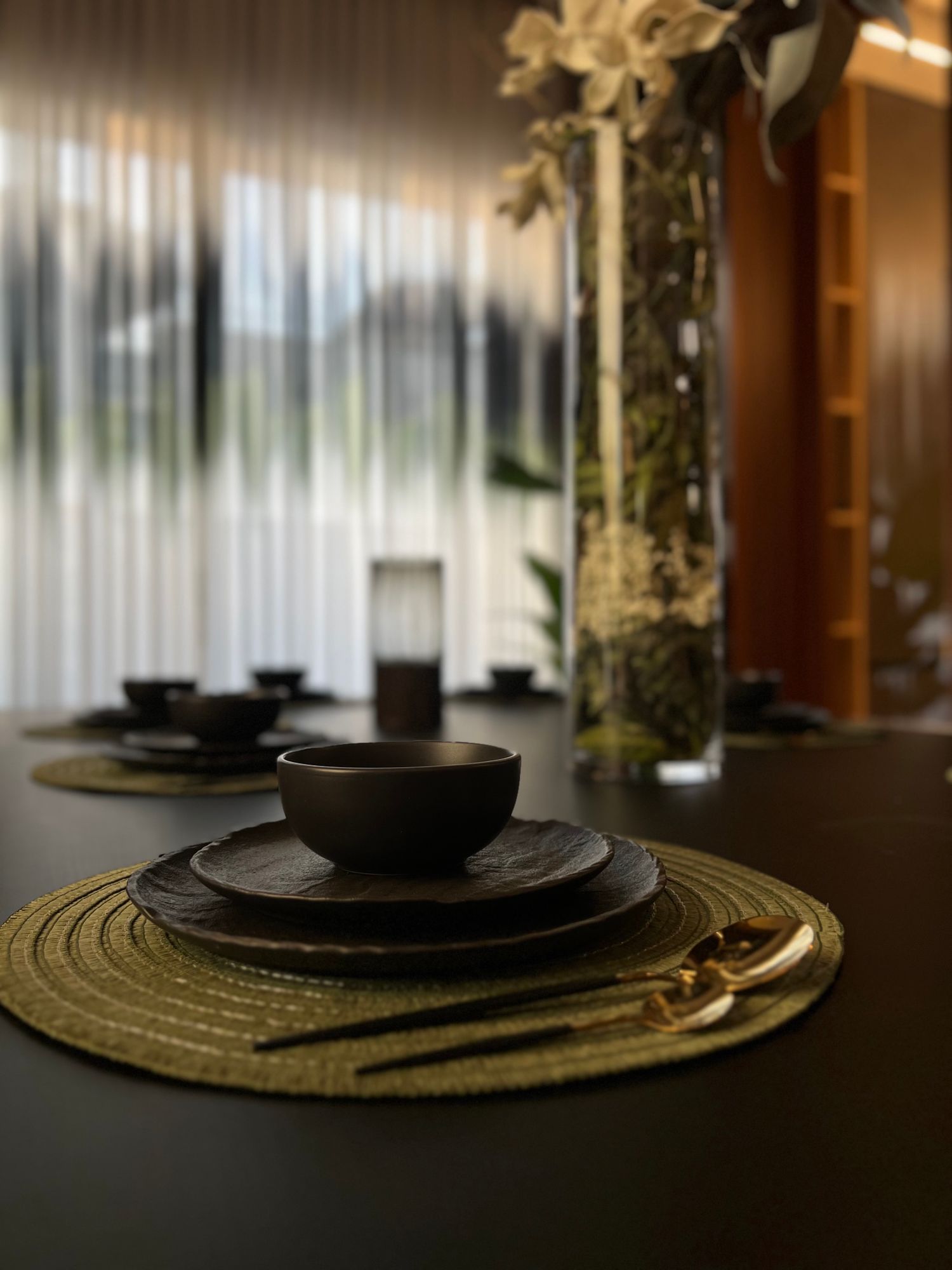 Dark ceramic dinnerware with cutlery arranged for an evening meal