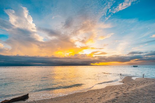 Captivating beach scene at sunset with dramatic clouds and vivid sky colors reflecting on the ocean.