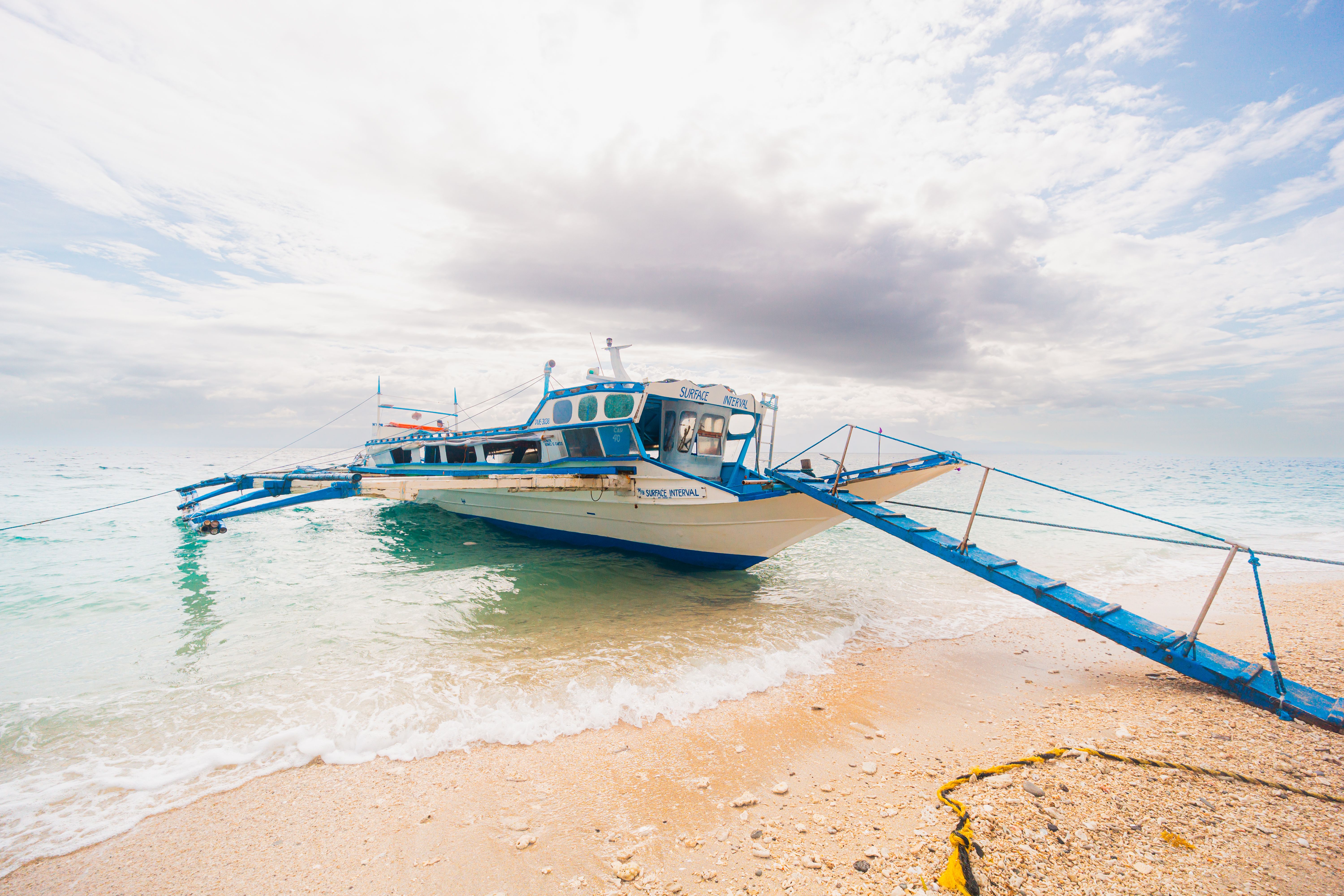 A traditional boat moored on a picturesque tropical beach under a bright sky.