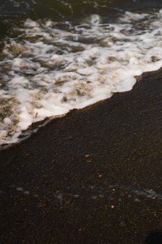 Close-up of gentle ocean waves washing over a sandy beach, capturing the serene rhythm of the sea.