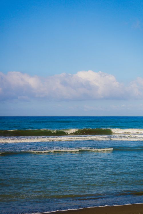 Free Tranquil ocean view with gentle waves and a vibrant blue sky, perfect for nature and travel themes. Stock Photo