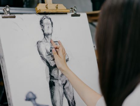 A focused artist sketching a human figure on canvas in a Shinjuku art studio in Tokyo, Japan.