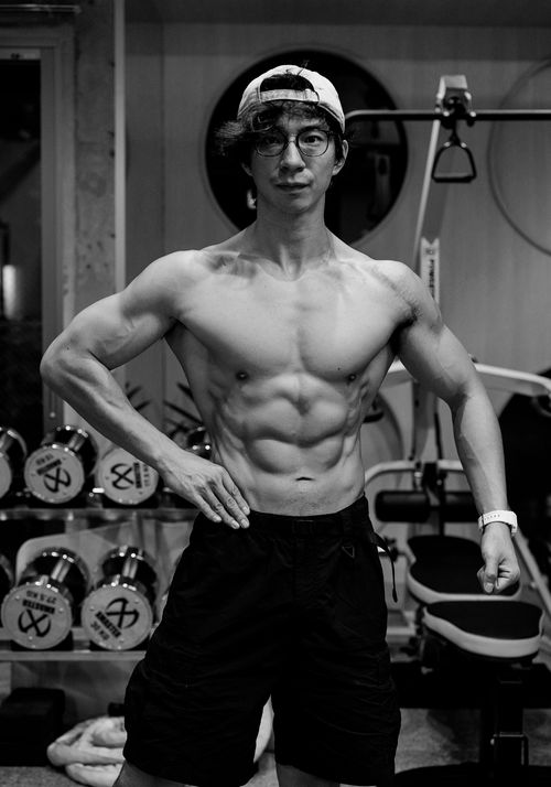 Free Fit man posing in a gym showcasing muscles with gym equipment in the background. Stock Photo