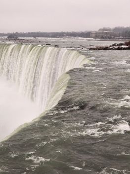 Stunning view of Niagara Falls during winter, showcasing powerful cascades and misty atmosphere.
