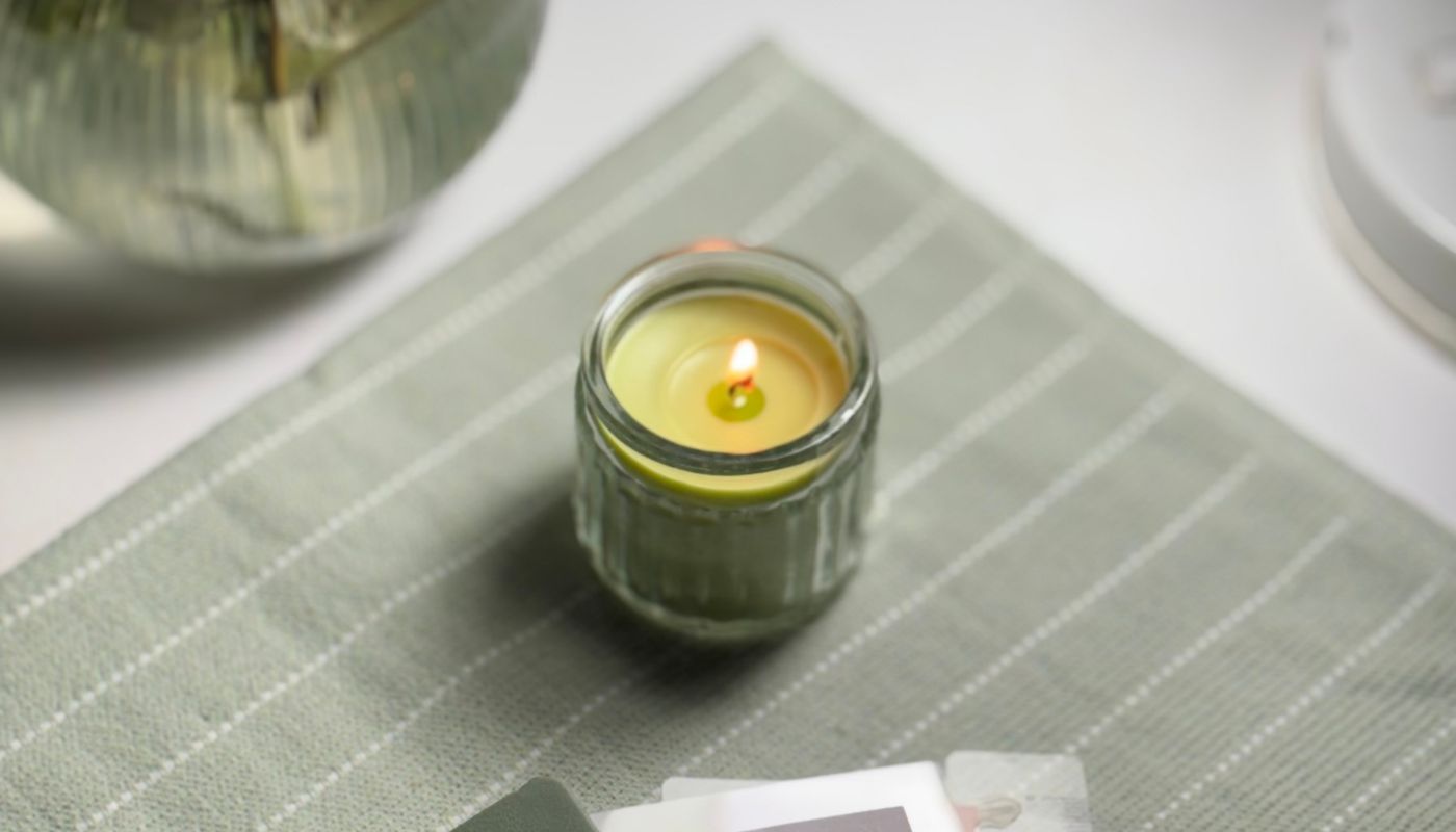 A lit candle on a folded cloth beside a notebook in low evening light