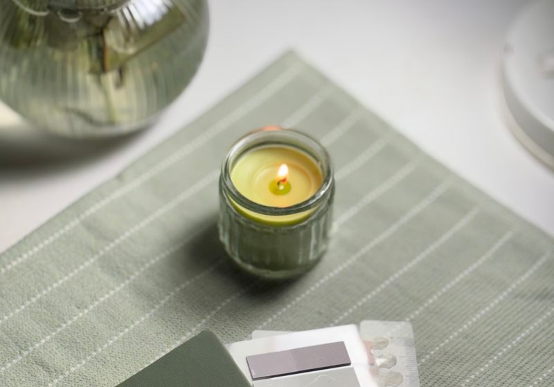 A lit candle on a folded cloth beside a notebook in low evening light