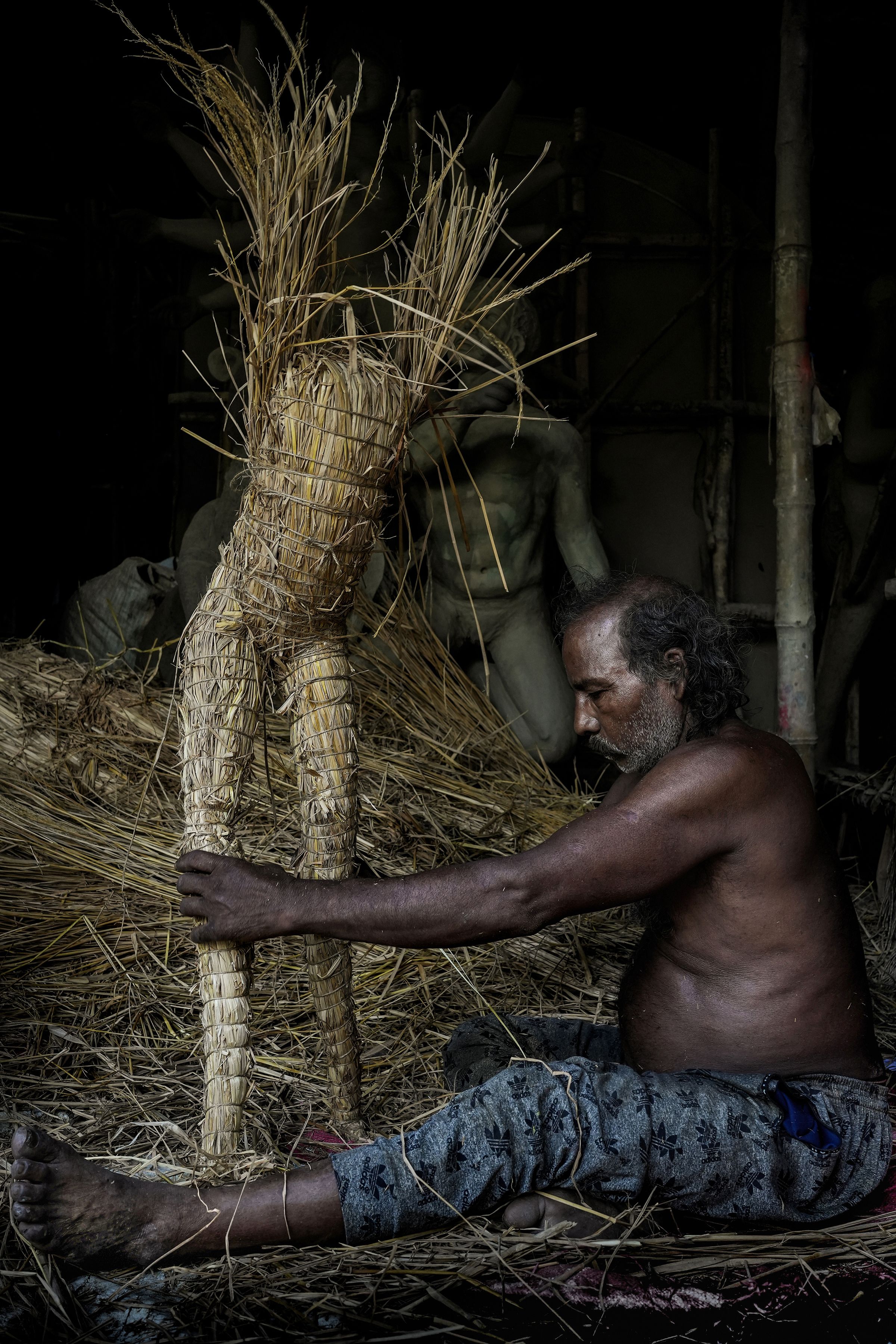 Craftsman shaping a straw idol in Chakla, India. Capturing cultural artistry.