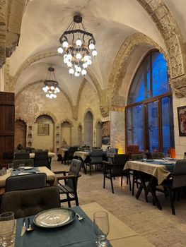 A sophisticated dining room with ornate arched stone ceilings and elegant chandeliers.