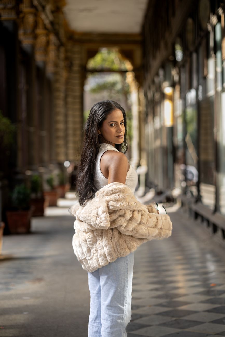 Stylish woman in casual attire strolls through a historic Mumbai arcade, showcasing urban street style.