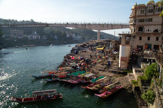 Captivating riverside view with colorful boats and bustling activity under a scenic bridge.