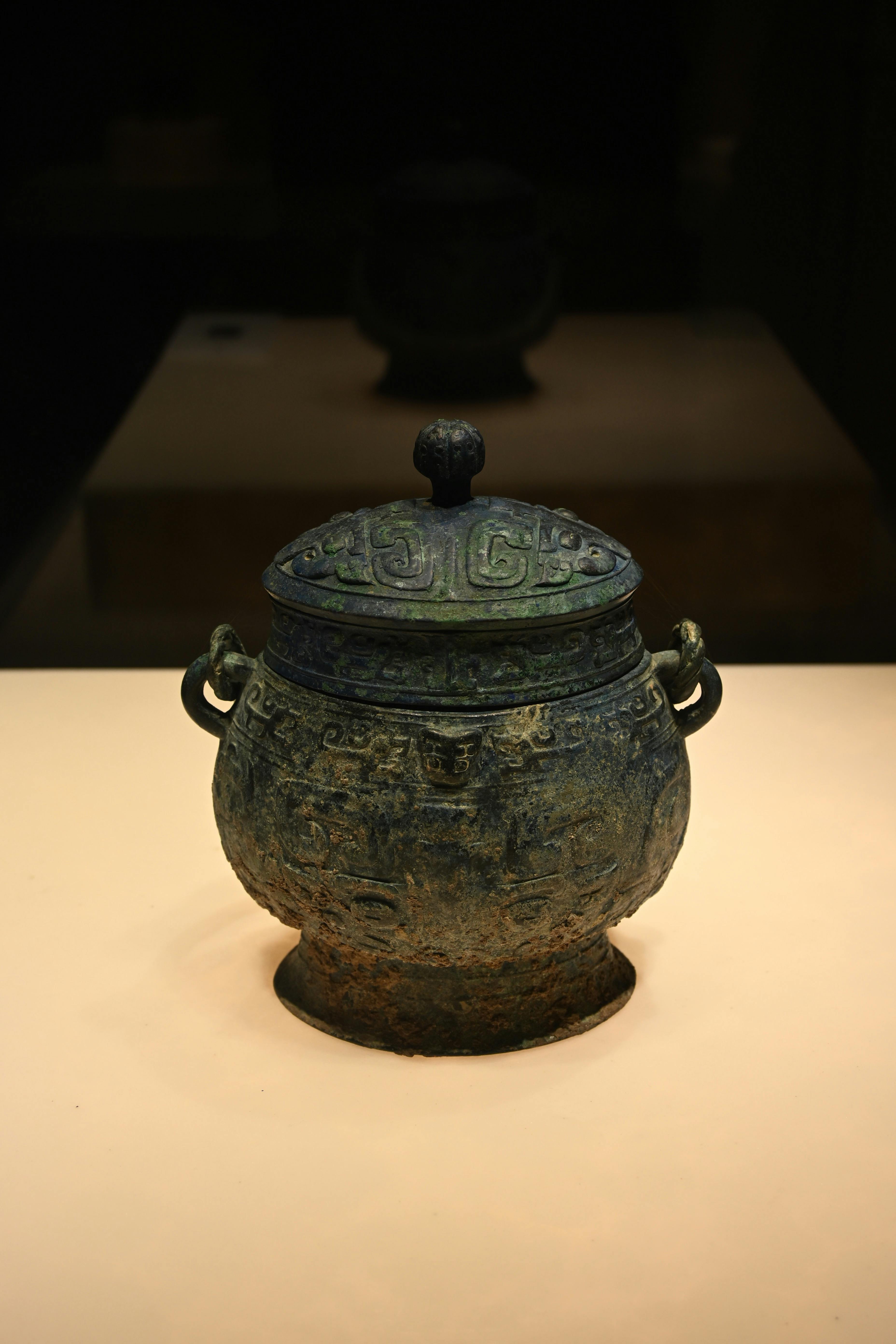 A detailed view of an ancient Chinese bronze vessel displayed in an art gallery setting.