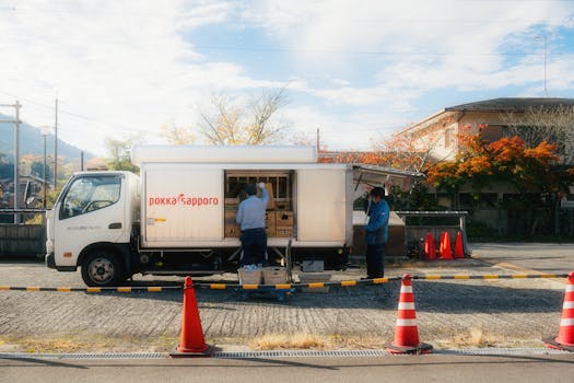 A delivery truck being unloaded in a Japanese suburb during autumn.