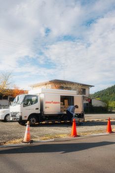 A mobile food truck parked on a street with a person and traffic cones under a sunny sky.