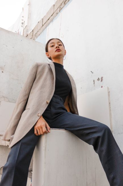 Low-angle portrait of a stylish woman in a chic outfit, exuding confidence and elegance.