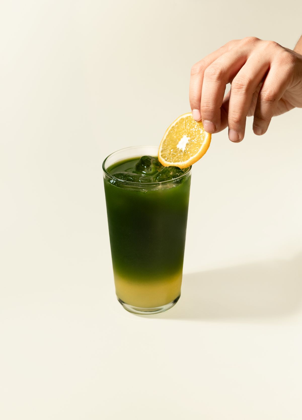 Matcha lemonade recipe in a clear glass with ice, green tea layer, and citrus slice