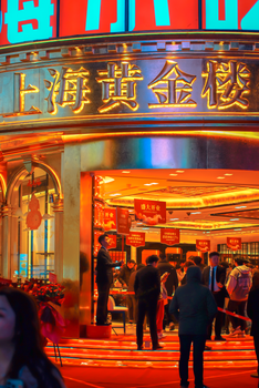Entrance to the bustling Shanghai Gold Exchange at night, lively atmosphere.