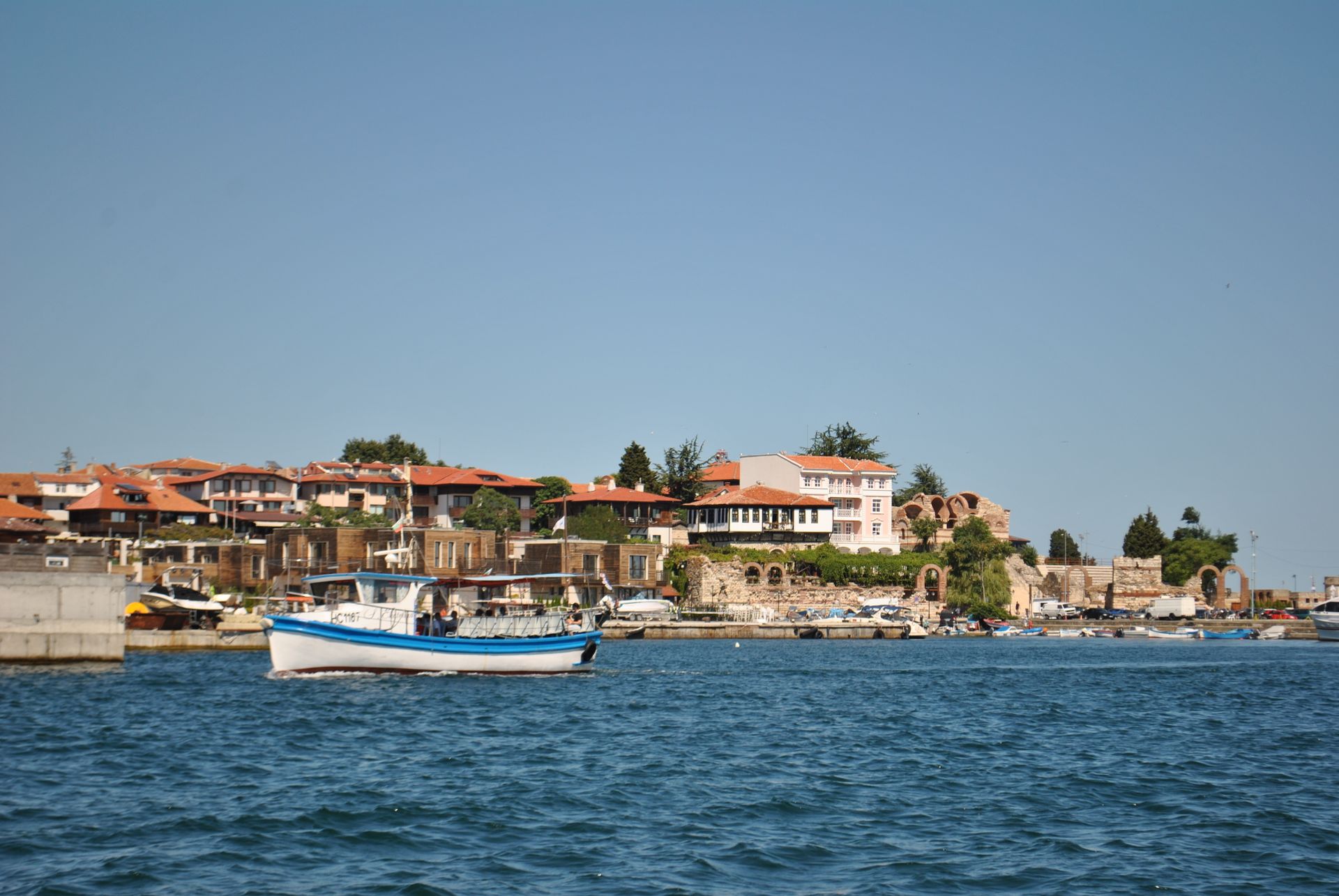 Black Sea water, a fishing boat, and the historic waterfront of Nessebar Old Town in Bulgaria