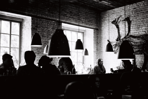 Free Black and white image of patrons in a stylish cafe with pendant lights. Stock Photo