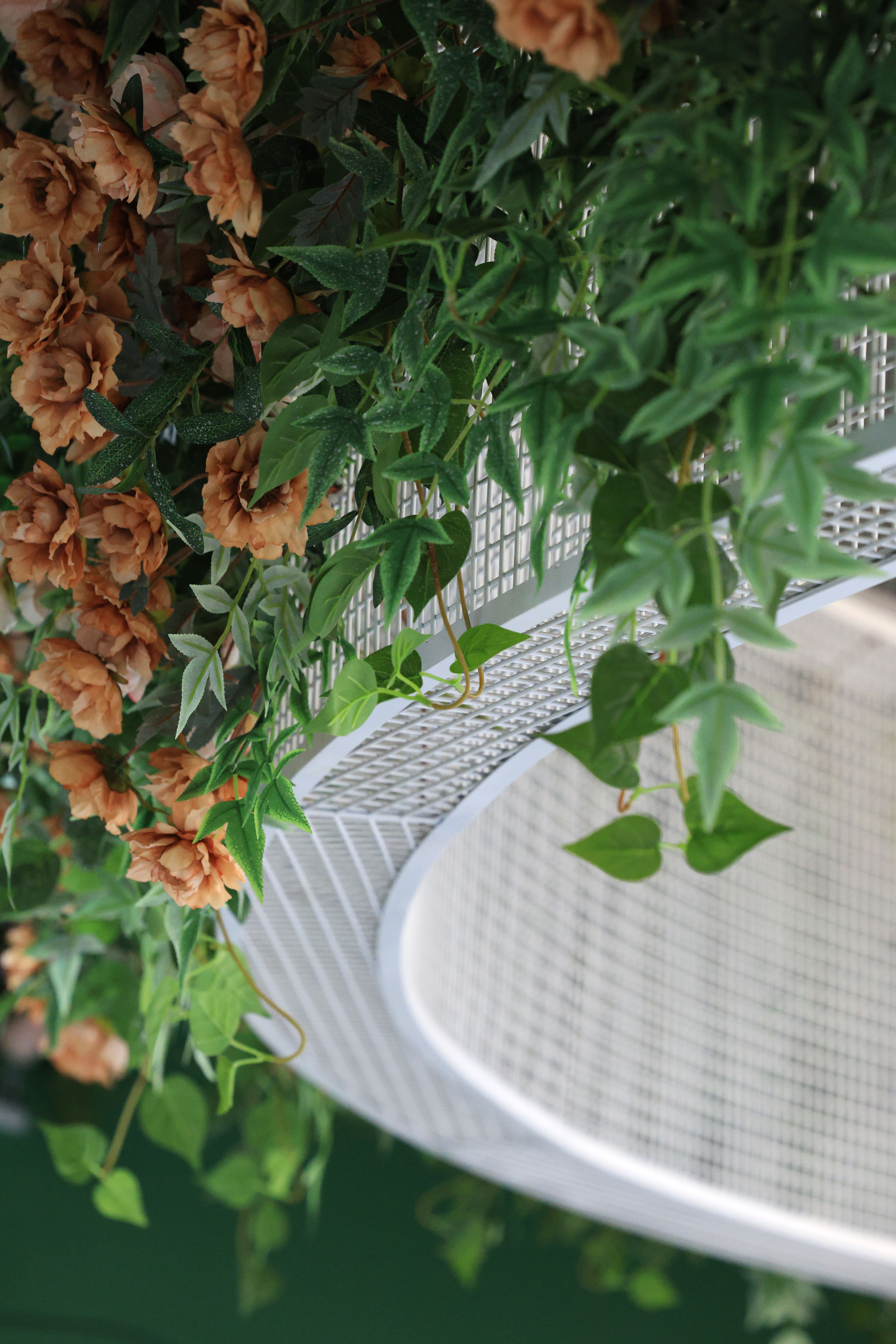Close-up of a decorative hanging basket with lush greenery and vibrant flowers displayed indoors.