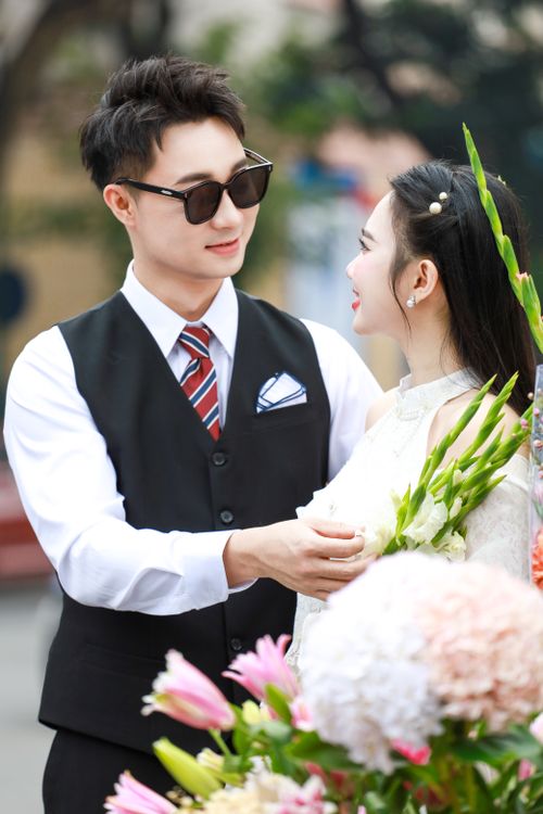 Free Charming wedding photo of a couple enjoying a moment with flowers in Hà Nội, Vietnam. Stock Photo