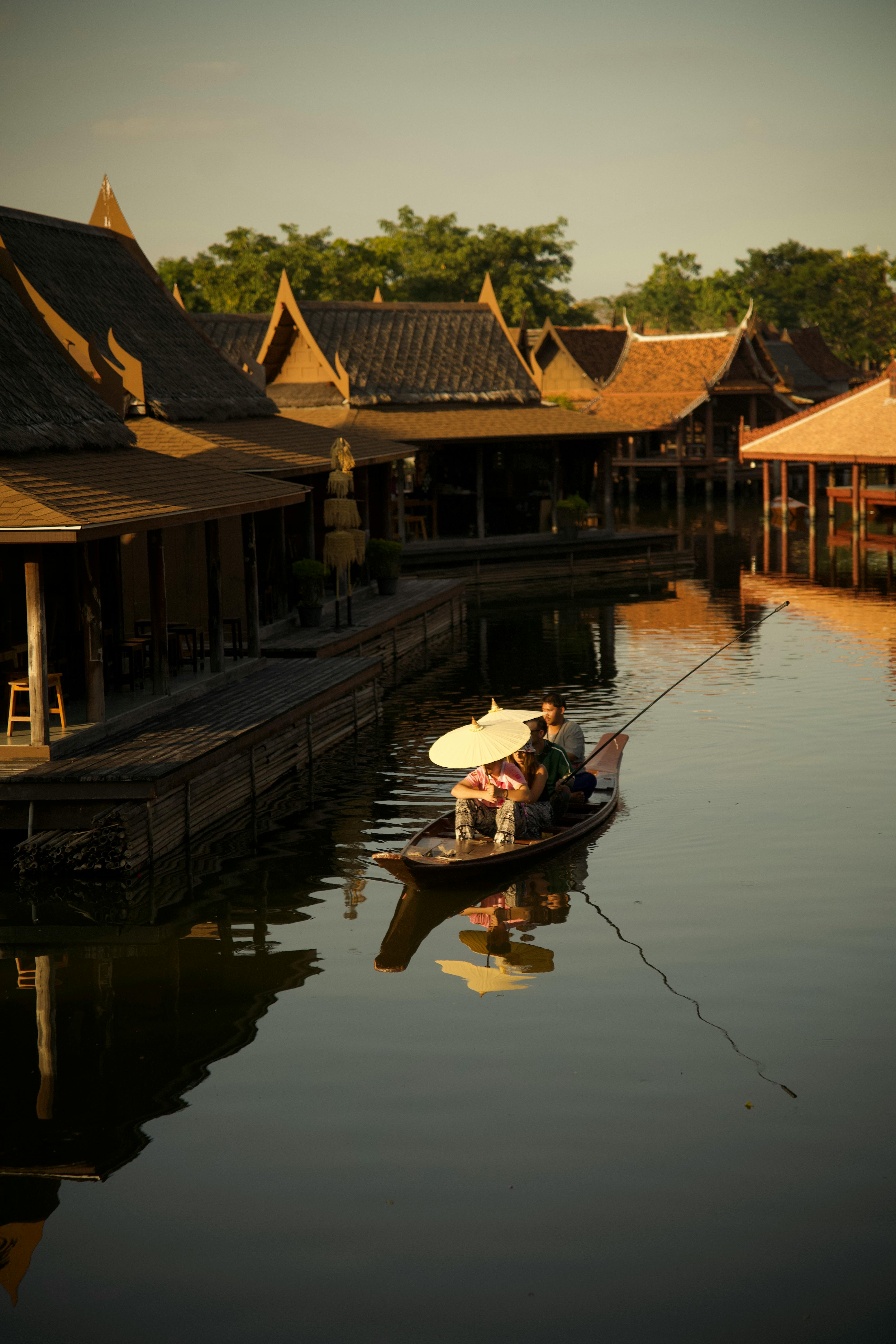 De franc Passeig tranquil en barca al capvespre pel tradicional mercat asiàtic amb arquitectura de fusta i reflexos panoràmics. Foto d'estoc