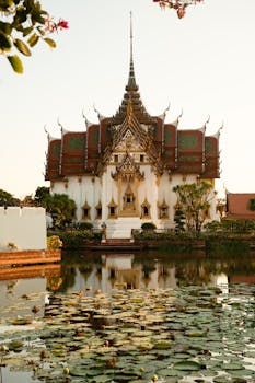 Beautiful Thai temple with intricate roof reflected in a serene pond surrounded by lily pads.