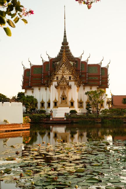 Beautiful Thai temple with intricate roof reflected in a serene pond surrounded by lily pads.
