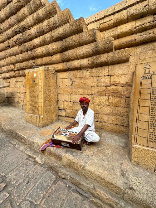 Free A musician plays harmonium by a historic wall, capturing cultural heritage. Stock Photo